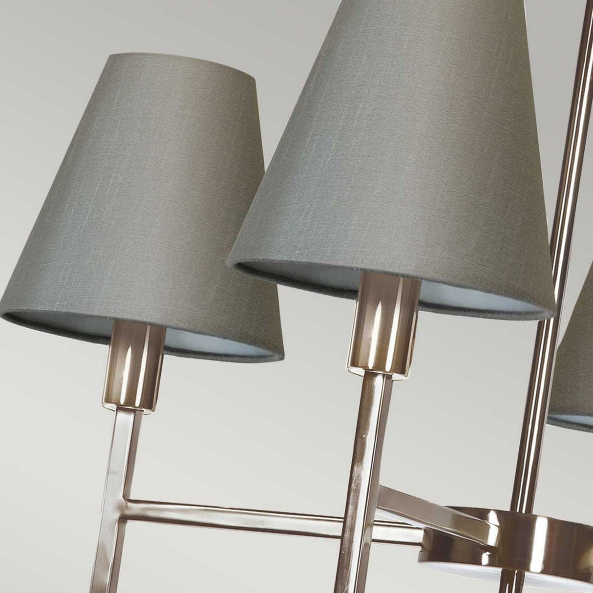 Close-up image of the Lucerne 4 Light Chandelier, featuring a modern luxury design with multiple grey fabric lampshades and glossy brushed nickel stands, set against a neutral background.
