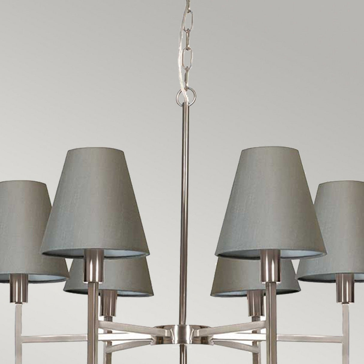 Discover the Lucerne 6 Light Chandelier - Brushed Nickel With Grey Shade, a modern masterpiece featuring a brushed nickel frame. It is adorned with six elegantly spaced grey fabric shades, set against a plain white background for timeless sophistication.