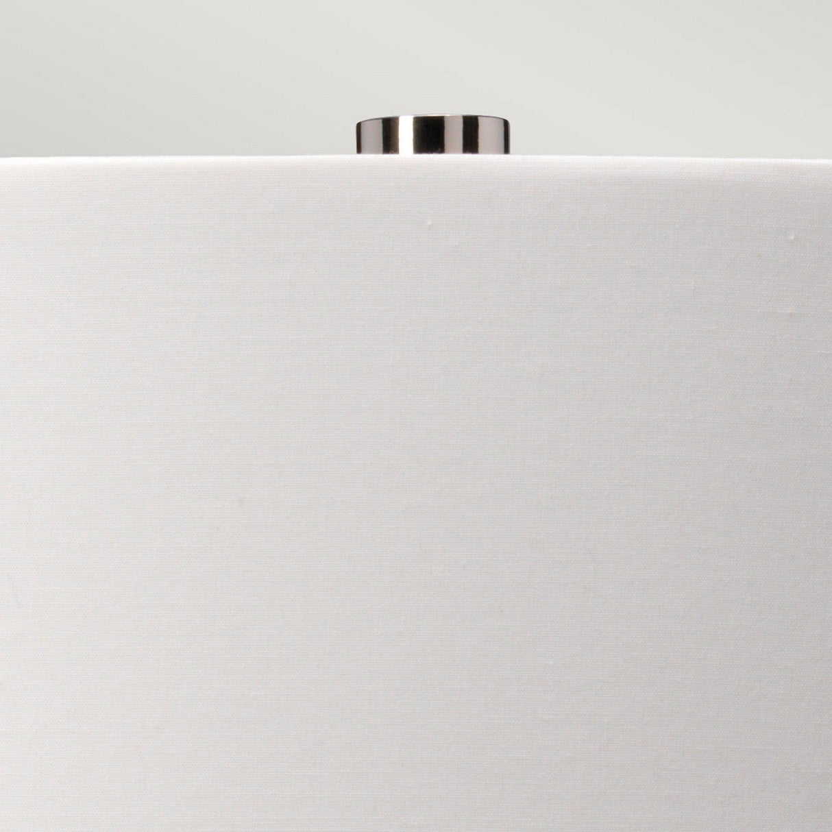 Close-up of the top of a white cylindrical lampshade, highlighting the modern design of the Luga Table Lamp - Polished Nickel with a central metallic knob. The light gray background enhances its minimalist charm, thoughtfully crafted using recycled materials.