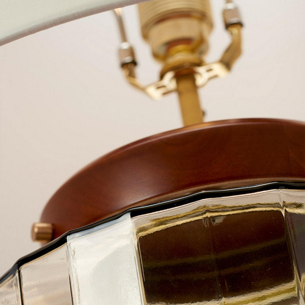 Close-up of the Luga Table Lamp in aged brass, showcasing its polished wooden accent and textured recycled glass lampshade. The focus is on the intersection of these elements, emphasizing the craftsmanship and eco-conscious design details.