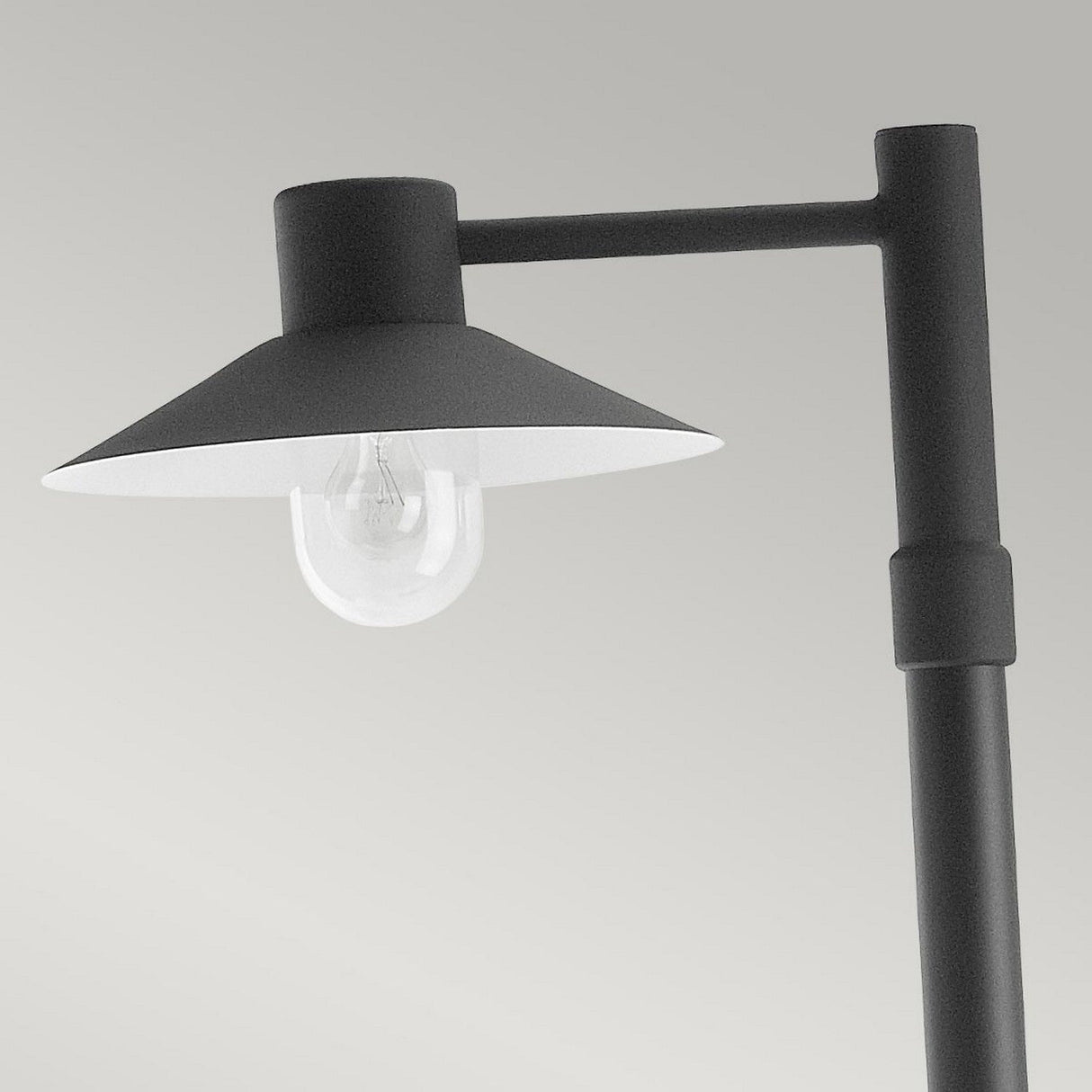 The Lund 1 Light Lamp Post in black, crafted from galvanized steel, showcases a minimalist design with a round shade and a clear bulb. Its sleek telescopic post stands out against a neutral background, enhancing any outdoor lighting setting.