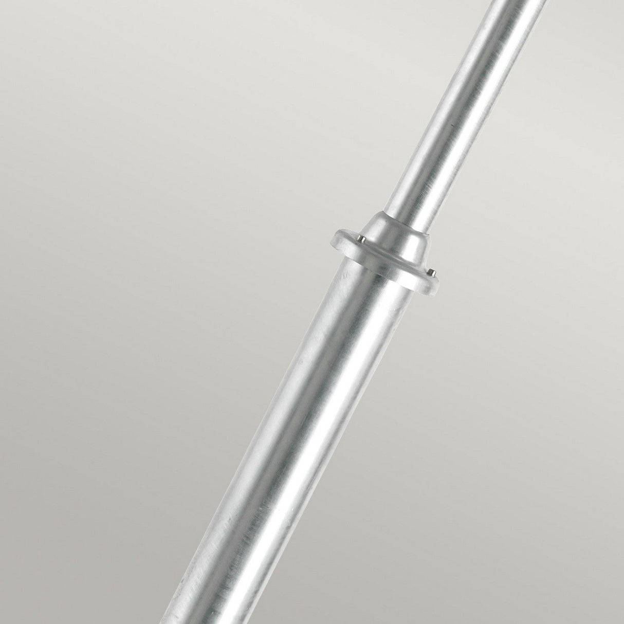 A Lund 1 Light Lamp Post - Silver, featuring a smooth, metallic finish, is positioned diagonally against a plain gray background, reminiscent of the sleek design often seen in a silver barbell. The collar of the lamp post is visible halfway along its length.