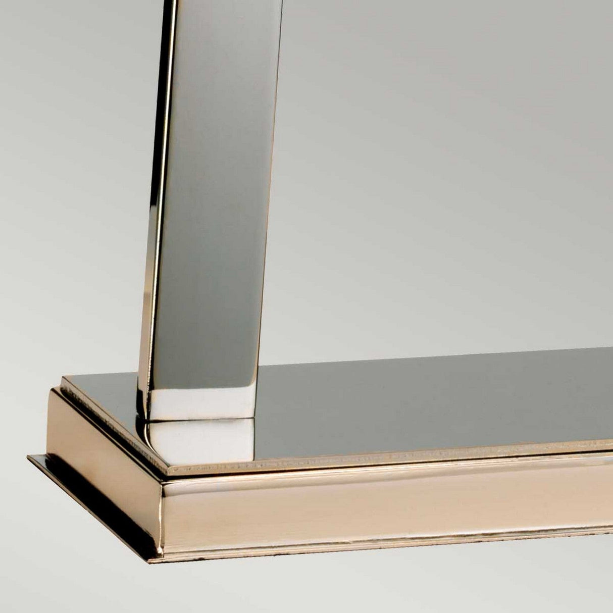 Close-up of a Magro 1 Light Table Lamp with a metallic frame and shiny, reflective finish in Polished Nickel. The design is minimalistic, showcasing clean lines characteristic of the lamp. A soft gradient in the background enhances its polished appearance.