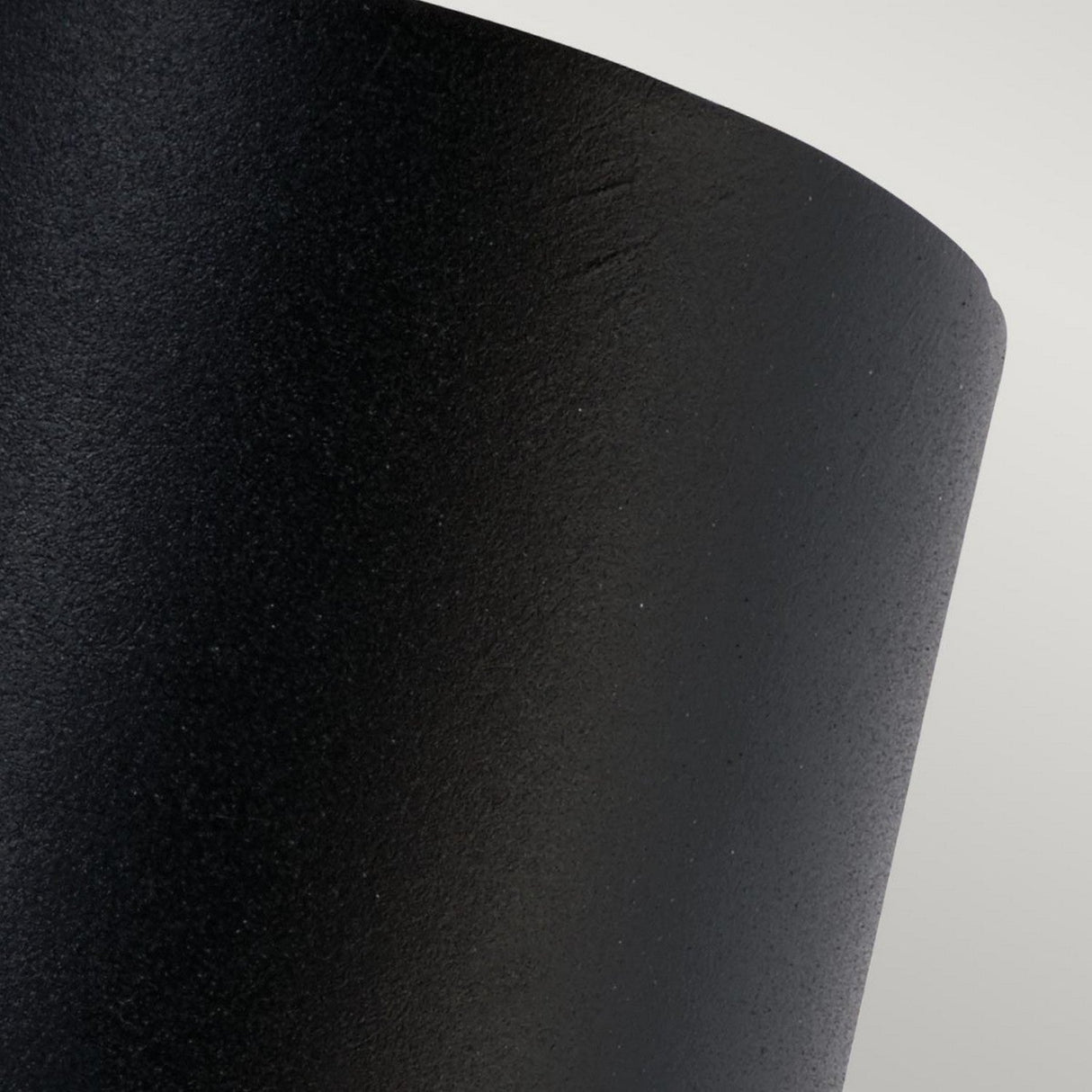 Close-up of a textured, curved black surface, reminiscent of the Mandal Outdoor LED Down Wall Light - Black, set against a light gray background. The image emphasizes the intricate details and sleek curvature of this IP44 Rated product.
