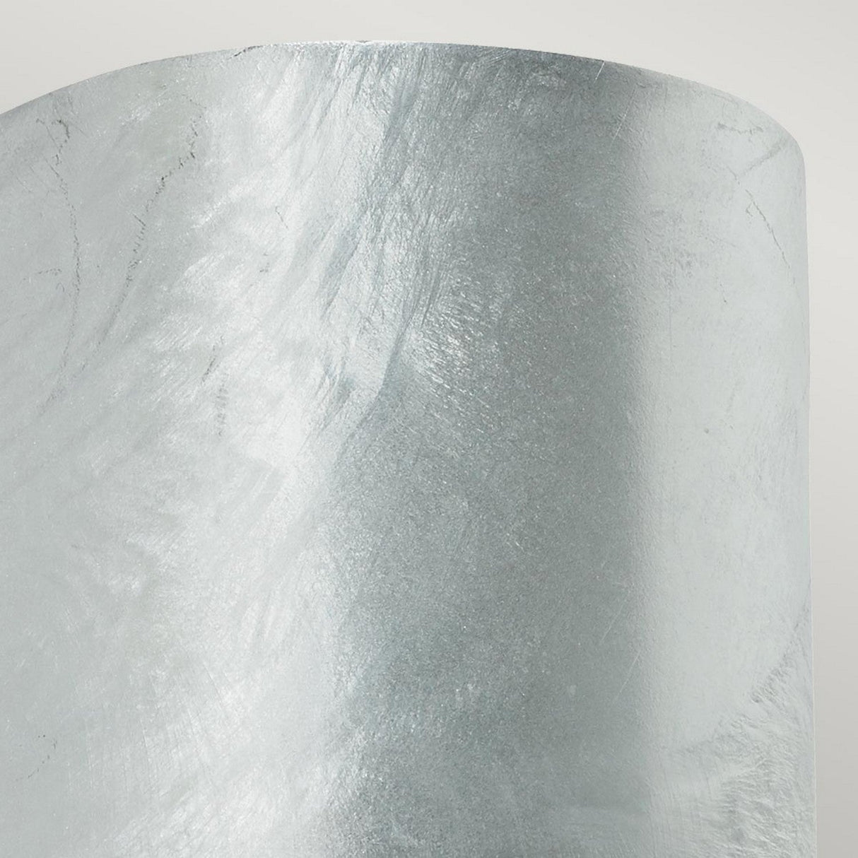 A close-up view of the Mandal Outdoor LED Down Wall Light in silver reveals a textured, metallic cylindrical surface with an iridescent sheen reminiscent of galvanized steel. The swirling patterns subtly reflect light, creating a smooth, abstract appearance that embodies modern design.