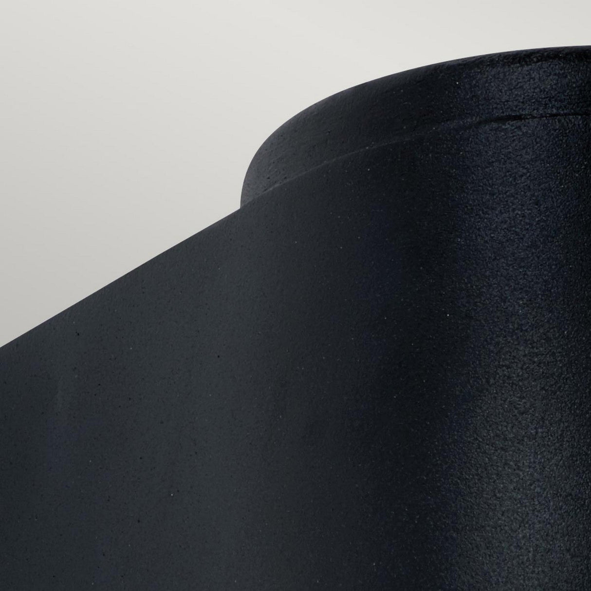 Close-up of the Mandal Outdoor LED Up/Down Wall Light in a matte black finish against a light grey background. This fixture features a smooth, slightly curved top edge, offering a sleek and modern look.
