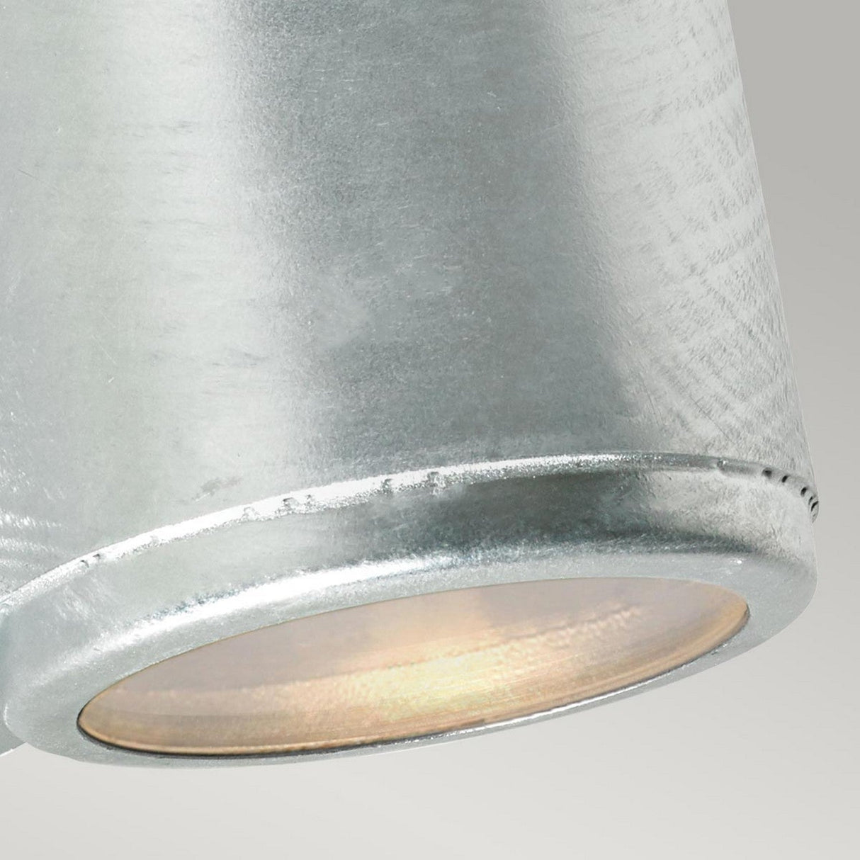 Close-up of the Mandal Outdoor LED Up/Down Wall Light in silver, featuring a metallic shade crafted from durable galvanized steel. It showcases a smooth finish with warm, energy-efficient illumination glowing inside, boasting a simple and modern design against a neutral background.