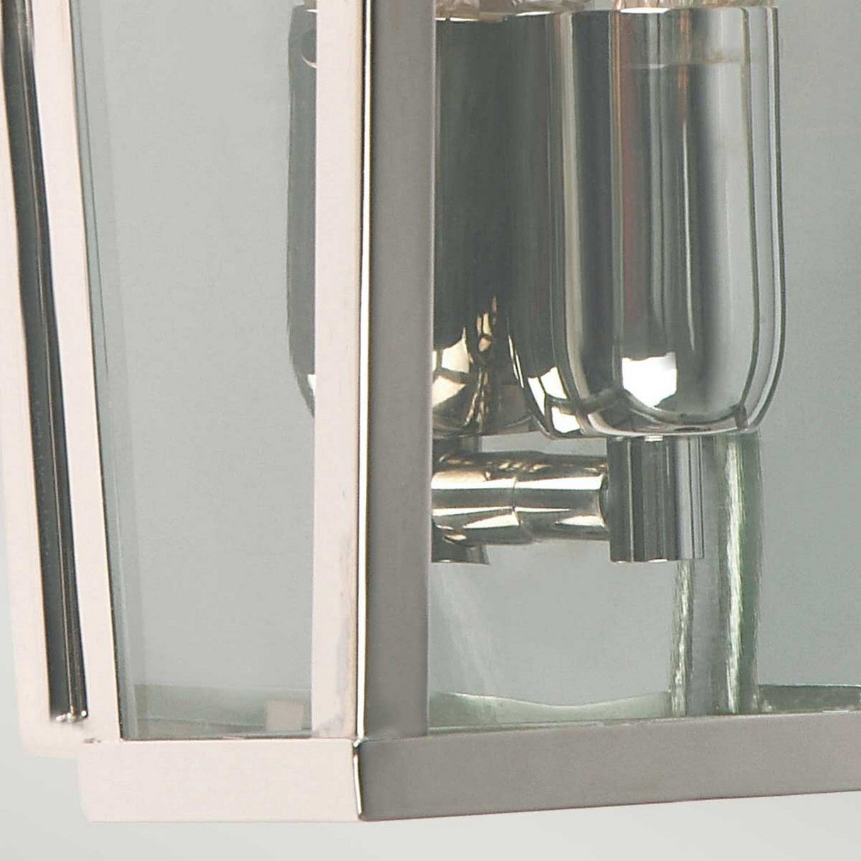A close-up view showcases the sleek design of the Mansion 1 Light Outdoor Wall Light in polished nickel, its reflective surface enhancing a minimalist aesthetic. Water cascades gracefully from the spout into a partially visible sink or basin, set against a soft gray background.