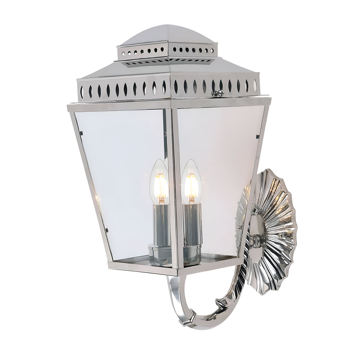 The Mansion 3 Light Outdoor Wall Light in polished nickel boasts a traditional lantern-inspired design with a rectangular glass enclosure and two candle-like bulbs, all elegantly mounted on an ornate floral-inspired base.