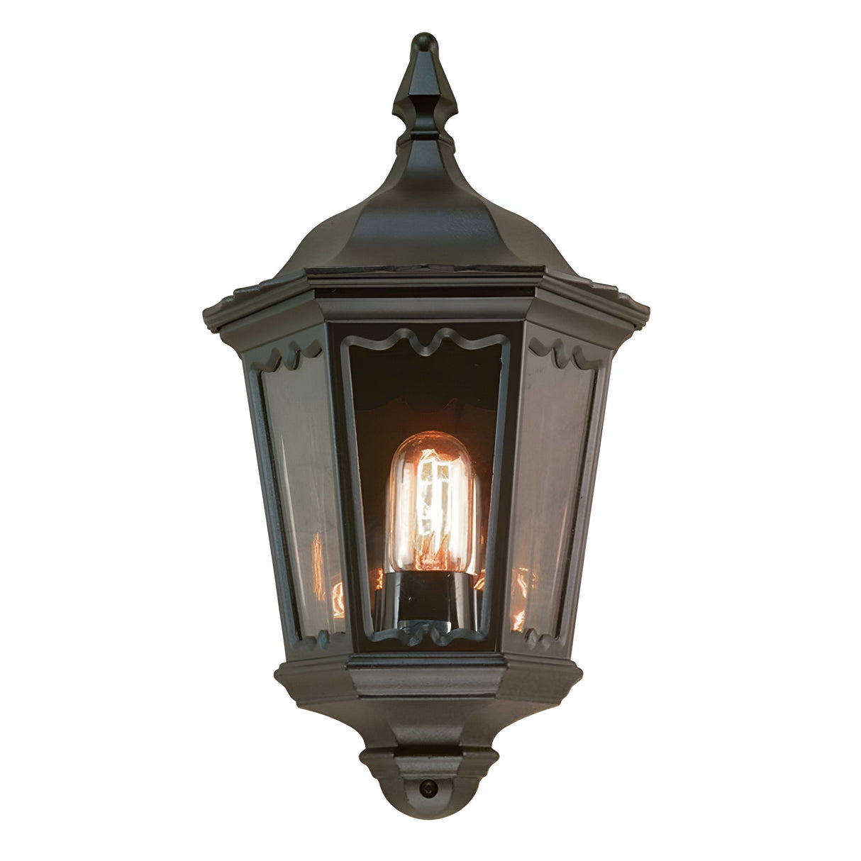 Introducing the Medstead 1 Light Outdoor Wall Light With PIR in Black, a vintage-style lantern ideal for exterior lighting. It features a black finish with a glass cover housing a single glowing bulb and includes decorative elements at the top along with a pointed finial.
