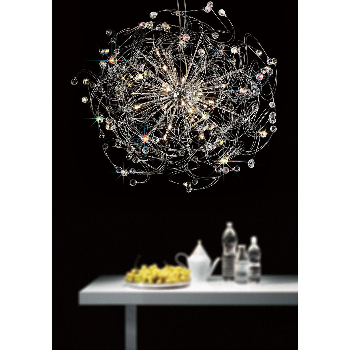 Diyas Messe 24 light crystal semi-flush ceiling light in polished chrome, with looping wires and faceted crystal spheres, shown above a white table.