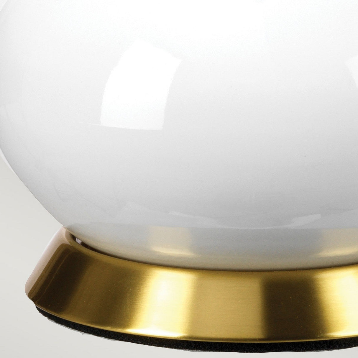 Close-up of the Milo 1 Light Table Lamp - Aged Brass/Brass, featuring a white spherical lamp with a shiny aged brass base against a light gray background. The surface of the sphere reflects light, creating subtle highlights reminiscent of an elegant design.