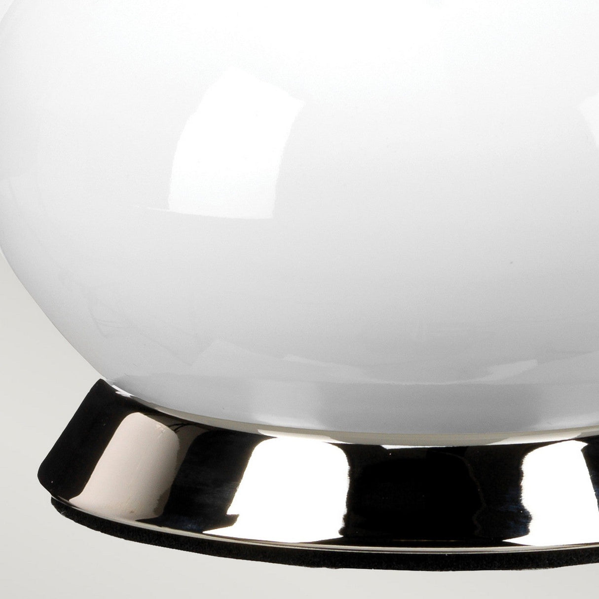 Close-up of the Milo 1 Light Table Lamp, featuring a round, white glass design with a shiny polished nickel base. Set against a plain background, the lamp's glossy surface and reflective foundation are prominently highlighted.