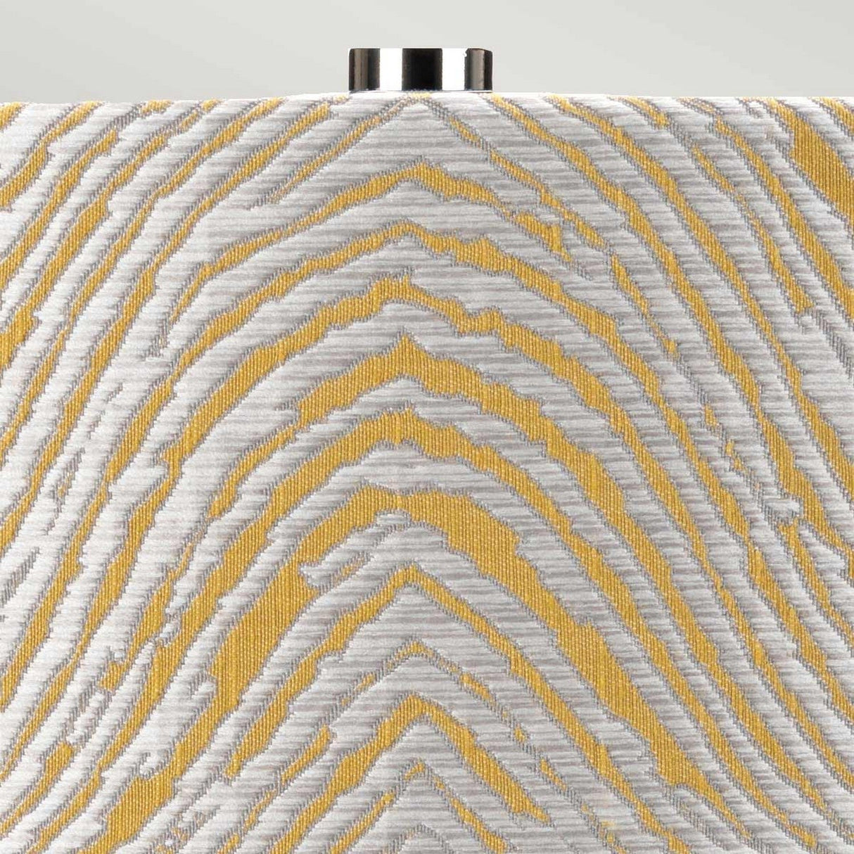 Close-up of a fabric with a textured pattern featuring interwoven golden-yellow and silver-gray threads, evoking the rippling motif found in the polished nickel Milo 1 Light Table Lamp - Polished Nickel/Yellow. This fabric's metallic sheen contrasts beautifully against a light background and pairs elegantly with a yellow drum shade.