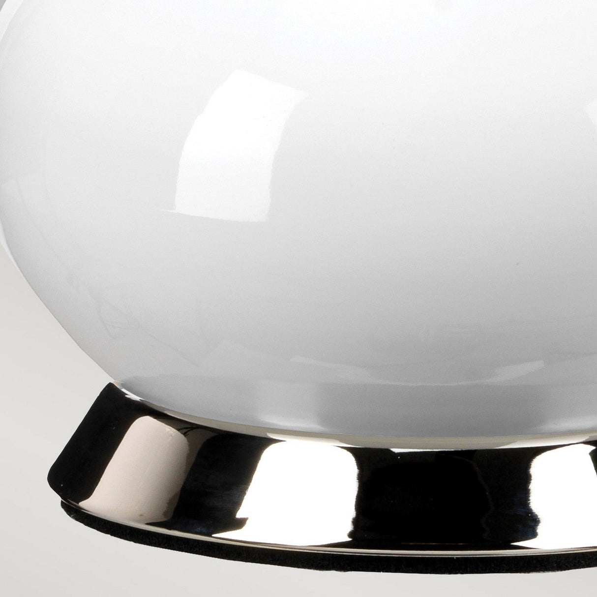 Close-up of the Milo 1 Light Table Lamp in Polished Nickel/Yellow, featuring a smooth, round white glass shade atop a polished nickel base. The surface reflects light, emphasizing the lamp's sleek and minimalist design.