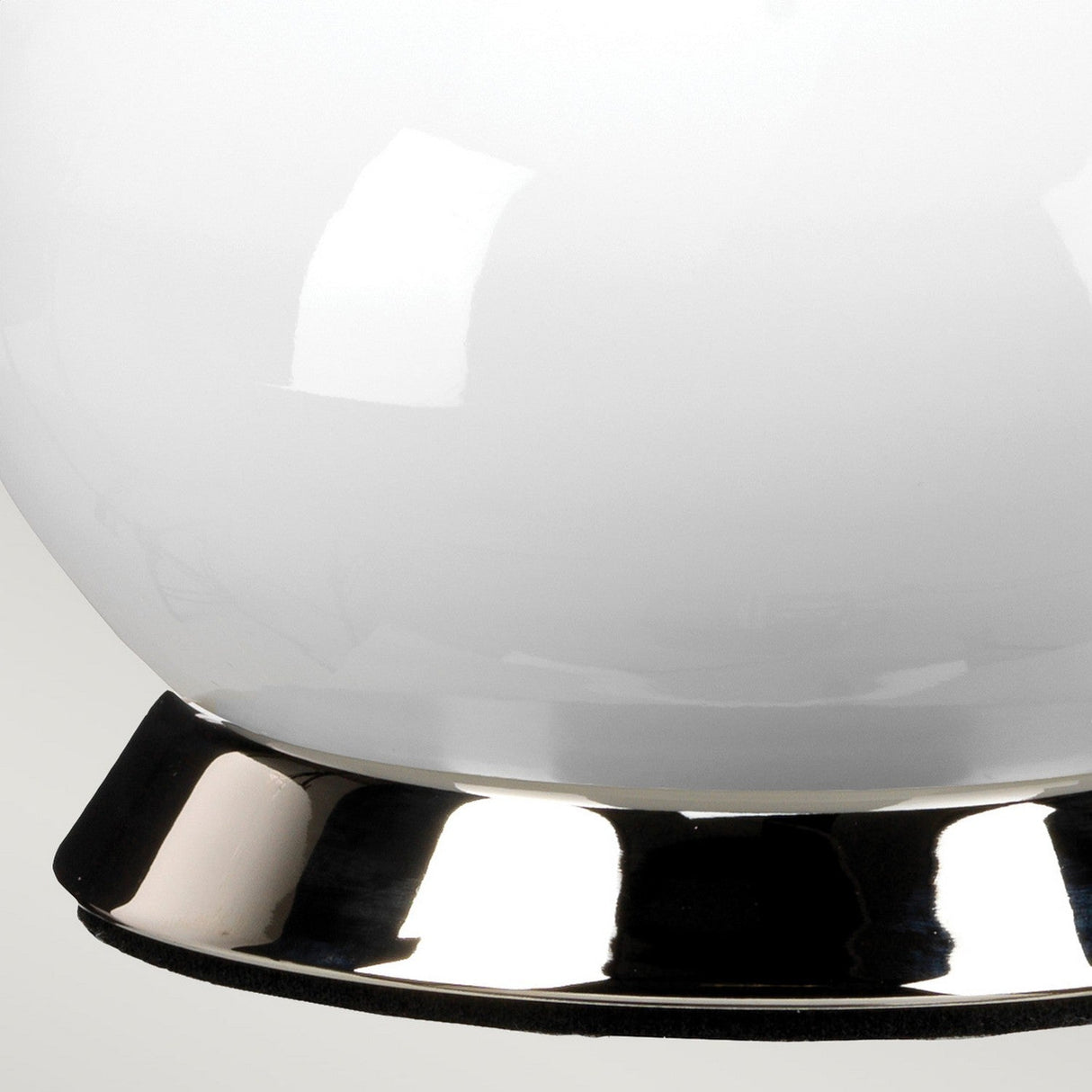 Close-up of the Milo 1 Light Table Lamp in polished nickel and silver, featuring a glossy white spherical shade. The reflective surface of the base creates subtle light reflections.