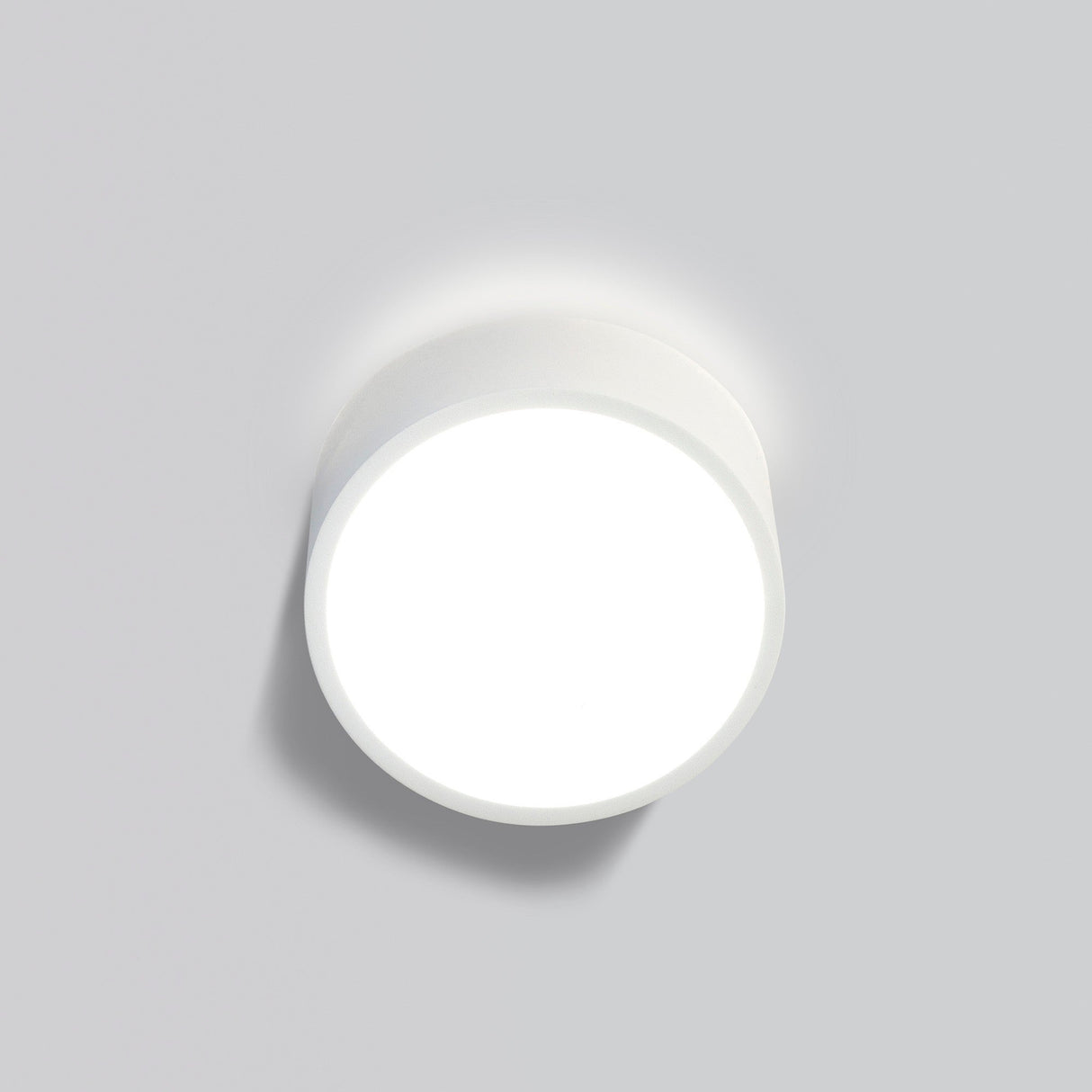 Mantra Mini Round 2 Light outdoor wall light in silver aluminium with circular opal white diffuser, shown lit against a light grey background.