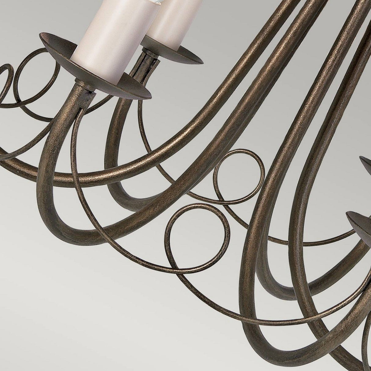Close-up of the Minster 6 Light Chandelier in black with a gold patina finish. It showcases elegant curved metal arms and candle-shaped light holders. The background is a neutral tone, emphasizing the intricate design of this semi-flush fitting fixture.