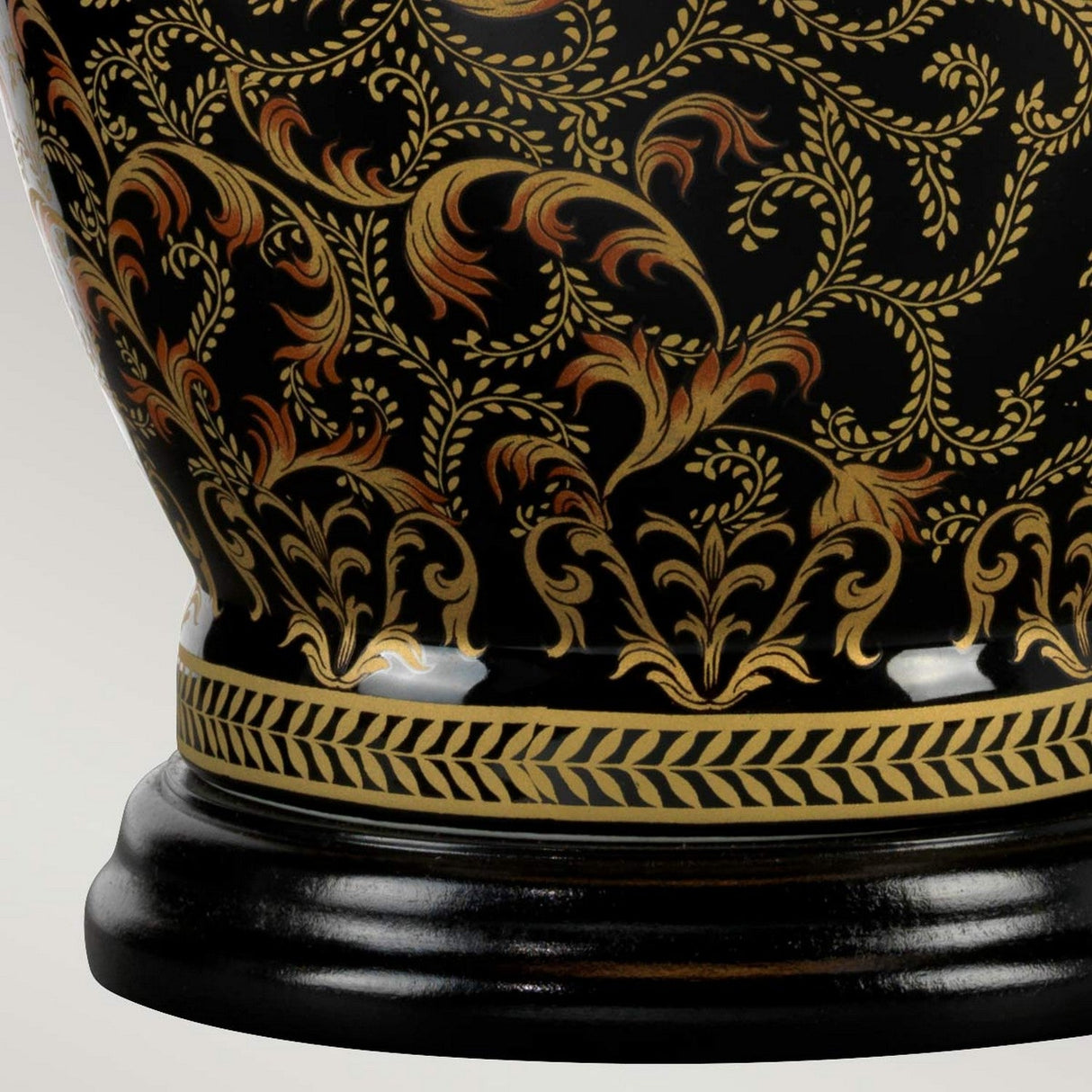 A close-up of an ornate ceramic vase that echoes the sophisticated style of Chinese porcelain, adorned with intricate golden floral patterns gracefully swirling on a black backdrop. The base showcases a geometric gold border, similar to the elegant design seen on the Morris 1 Light Large Table Lamp - Gold & Black.