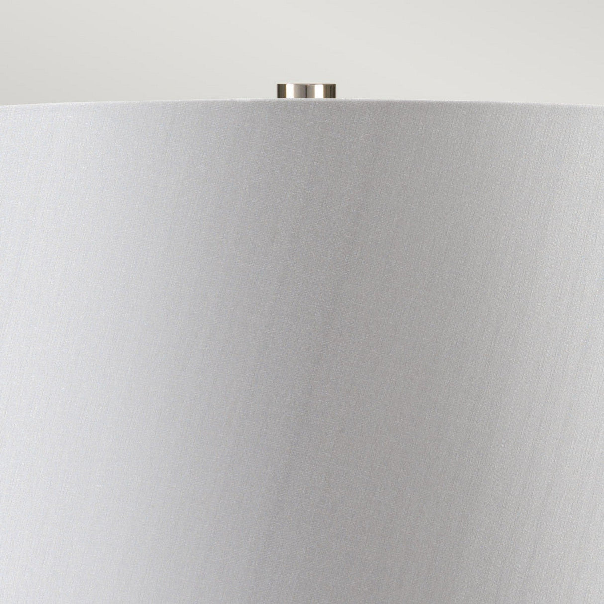Close-up of a Neptune 1 Light Table Lamp - Blue Glaze, showcasing a light gray lampshade with a smooth texture. The design includes a small, silver knob at the top center against a light gray background and is enhanced by polished nickel accents.