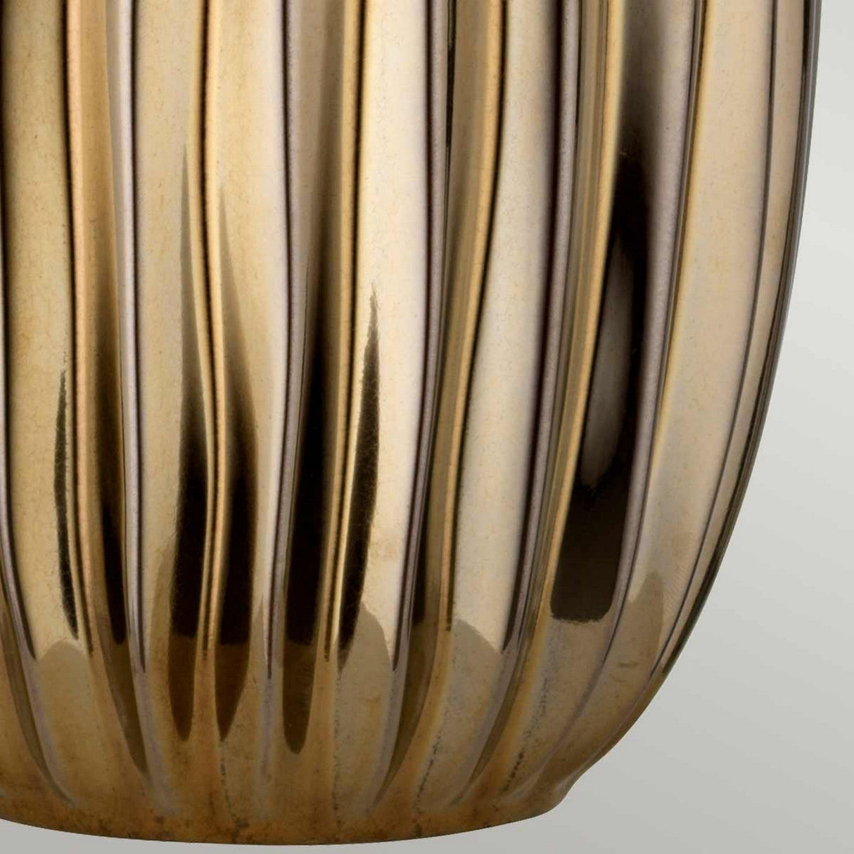 Close-up of a shiny, bronze ceramic vase with vertical ribbed patterns, reminiscent of the elegant Newham 1 Light Large Table Lamp. The surface reflects light, creating various shades of bronze against a soft gradient of gray tones.