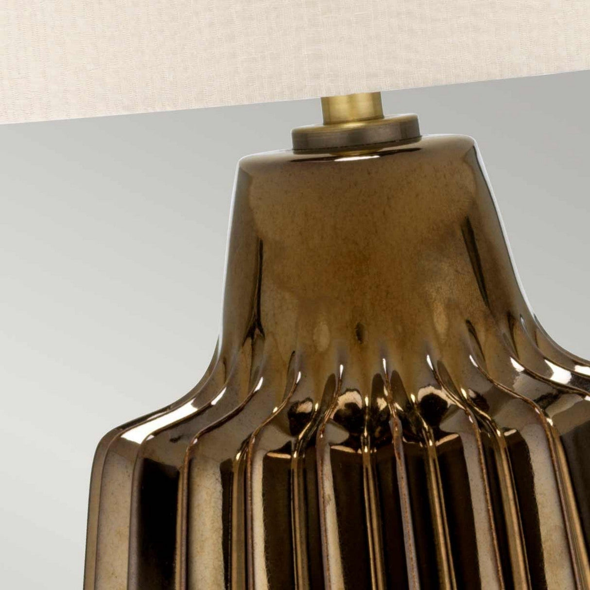 Close-up of the Newham 1 Light Large Table Lamp in Bronze Ceramic with a base that displays vertical ridges and grooves for added texture. The Pearl Shade is partially visible at the top, and the lamp is set against a neutral background.