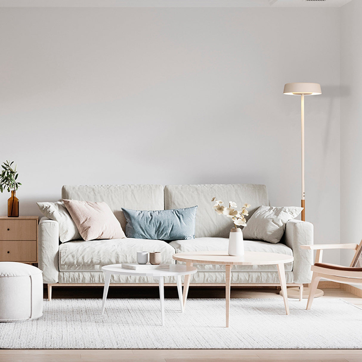 A modern living room with a light beige sofa, pastel cushions, two round coffee tables, a small plant, minimalistic soft-toned decor, and the Noa II Touch Dimmer LED Floor Lamp 15W 3000K in White & Beech.