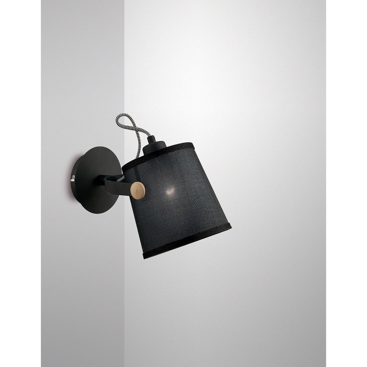 Mantra Nordica single spotlight wall light with matt black mesh shade, beech wood pivot arm and braided cable, mounted on a white wall.