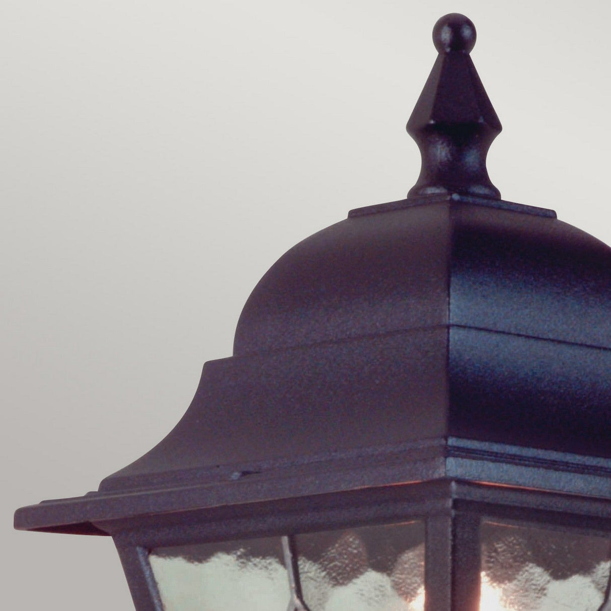 Close-up of the Norfolk 1 Light Up Outdoor Wall Light in black against a gray background. This vintage-style lantern showcases hand-leaded glass and a decorative top, offering classic elegance.