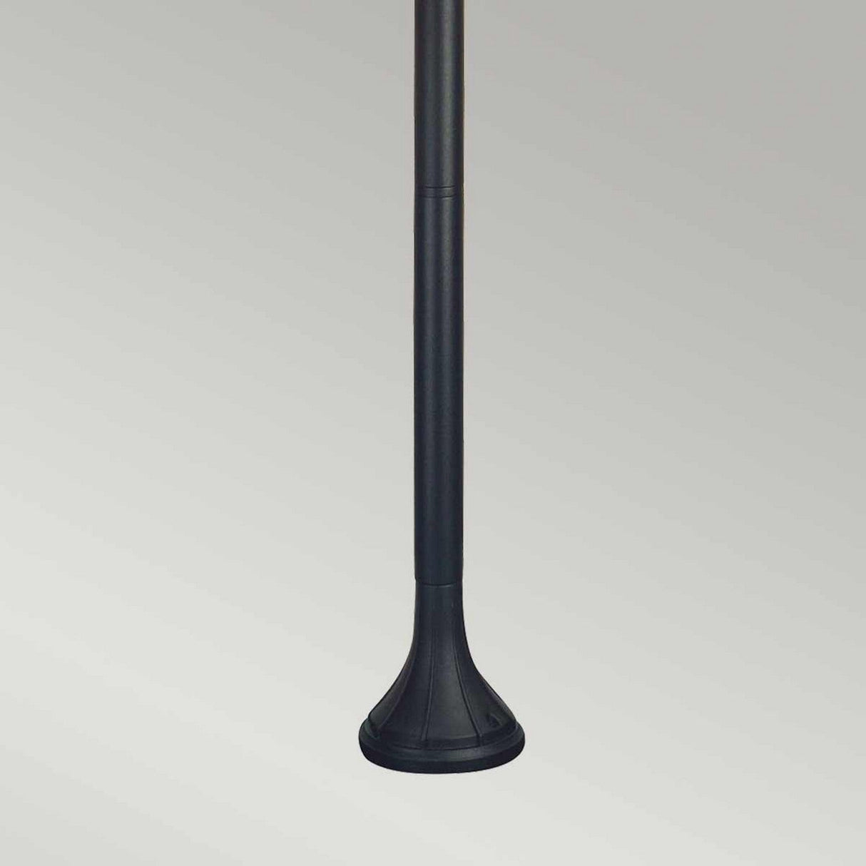 A long, slender black pole with a flared base set against a light gray background epitomizes the simplicity and minimalism of the Norfolk 1 Light Pillar Light - Black. Ideal for outdoor lighting, its design effortlessly merges style with functionality.