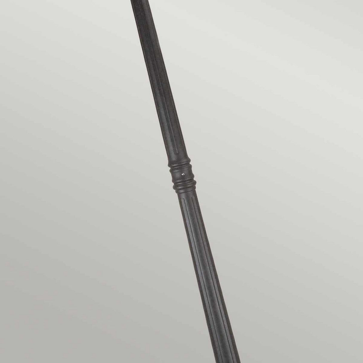 A Norfolk 3 Light Lamp Post in black metal stands diagonally across a light gray background, featuring a classic ridged design reminiscent of traditional lamp posts.