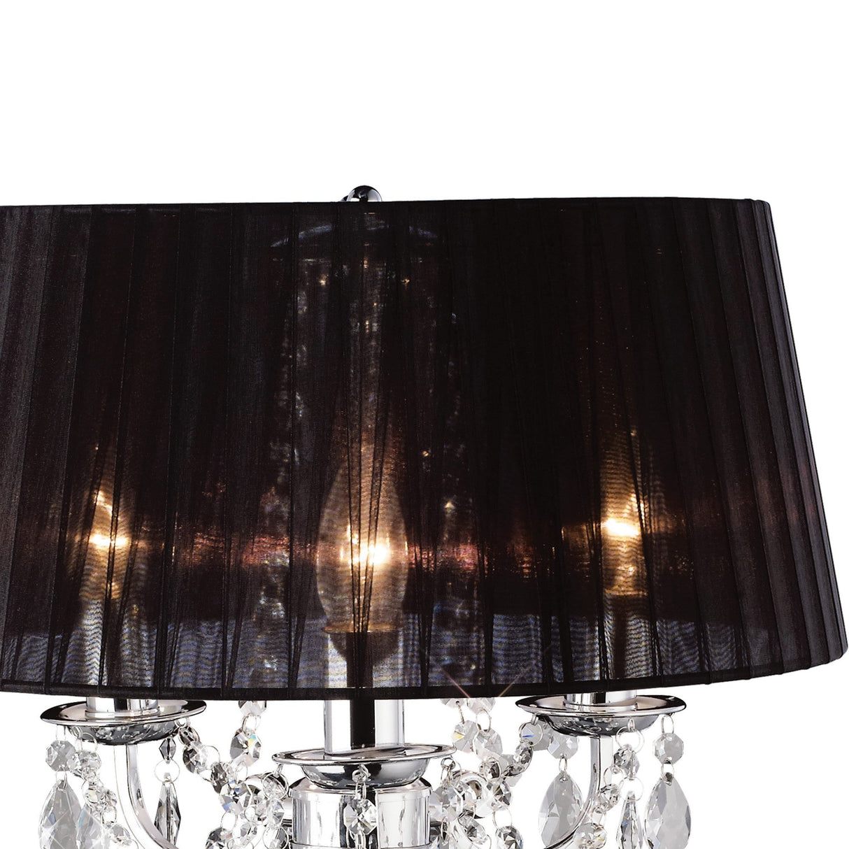 The Olivia 3 Light Crystal Table Lamp features polished chrome and a black pleated shade. Crystal accents dangle below the shade, reflecting the lamp's light beautifully against a plain white backdrop.