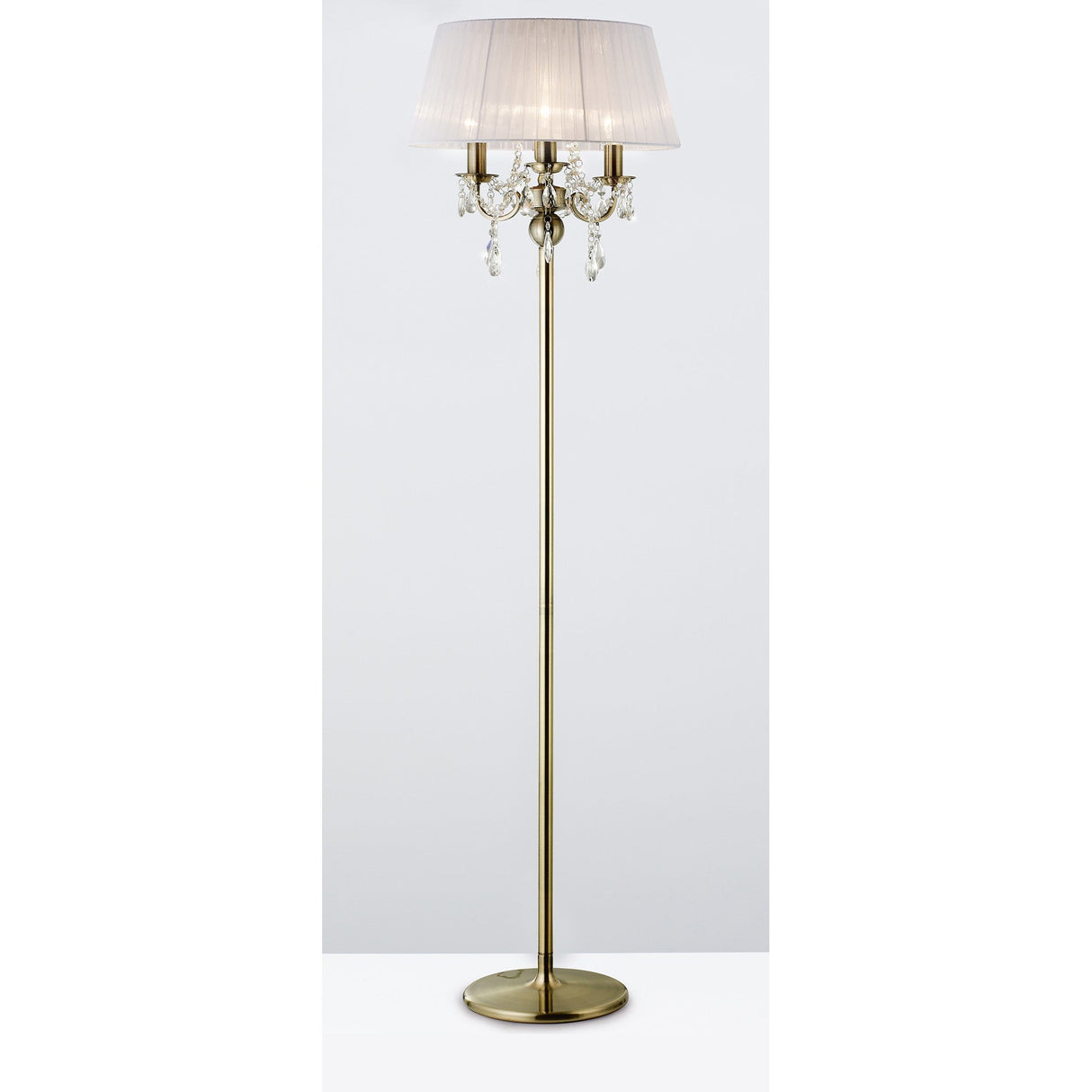 The Olivia 3 Light Crystal Floor Lamp features an antique brass finish, a round base, white pleated shade, and crystal accents hanging below the shade.