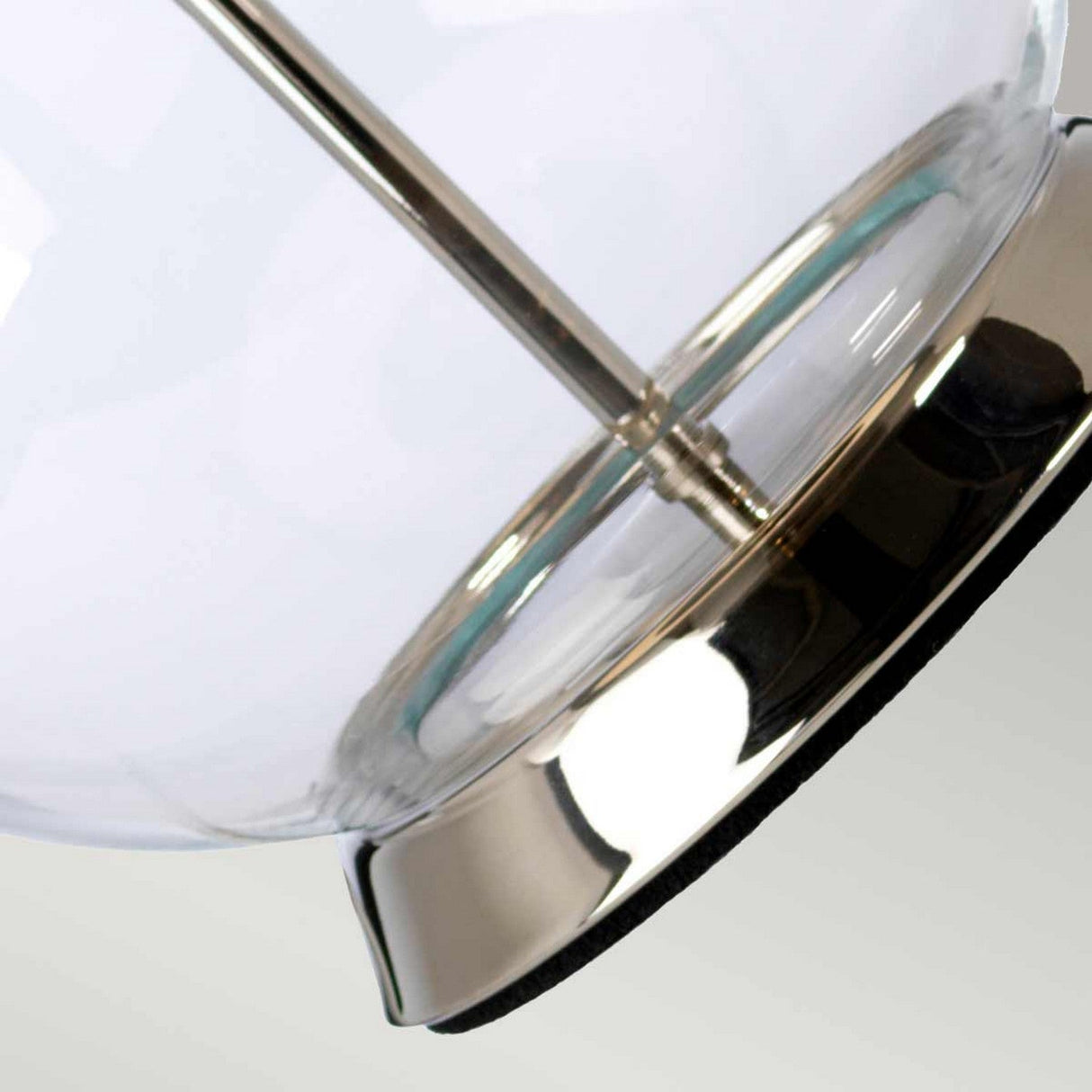 Close-up of the metallic base of the Orb 1 Light Table Lamp, which features a polished nickel finish that gleams with a shiny silver tint, and the clear glass above allows light to pass through, beautifully complemented by an elegant black shade.
