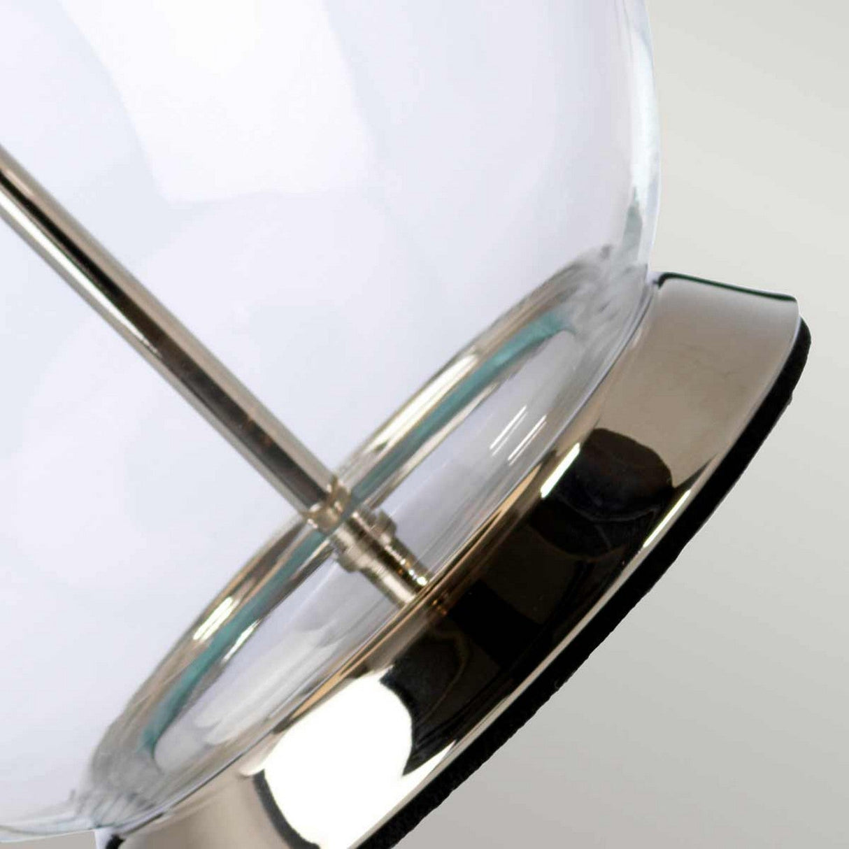 Close-up of the Orb 1 Light Table Lamp, highlighting its polished nickel base and slender central support rod. The lamp's sleek surface beautifully reflects light, while its glossy, polished finish enhances the elegance of its stylish white shade.