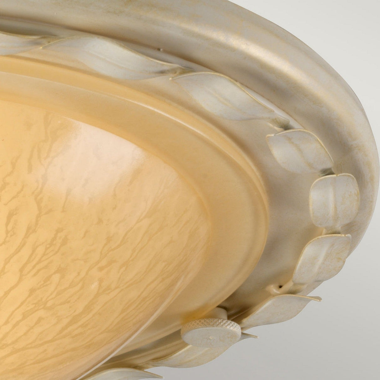A close-up of the Olivia 1 Light Flush in an Ivory/Gold Patina showcases its elegant design, featuring a beige marbled glass dome and a decorative metallic rim with leaf accents. This handmade light fixture is attached to a wooden ceiling, creating a classic and sophisticated look.