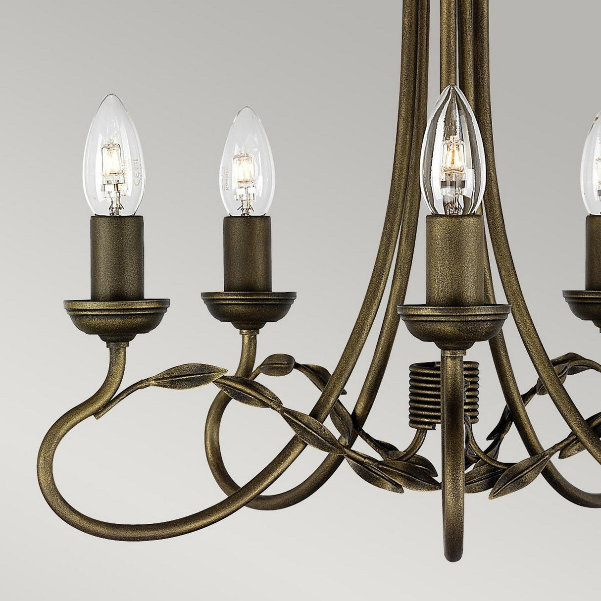 Close-up of the handmade Olivia 5 Light Chandelier with vintage-style bronze metal arms and leaf decorations, finished in a black/gold patina, featuring four candle-shaped light bulbs against a plain gray background.