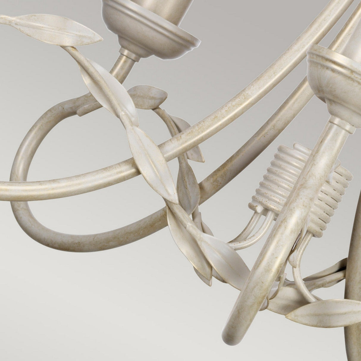 Here's a close-up of the Olivia 5 Light Chandelier - Ivory/Gold Patina, showcasing its swirling ivory-colored metal arms accented with a subtle gold patina and leaf details. The candle-like light holders contribute an elegant and classical style, ideal for transitional interiors with neutral backgrounds.