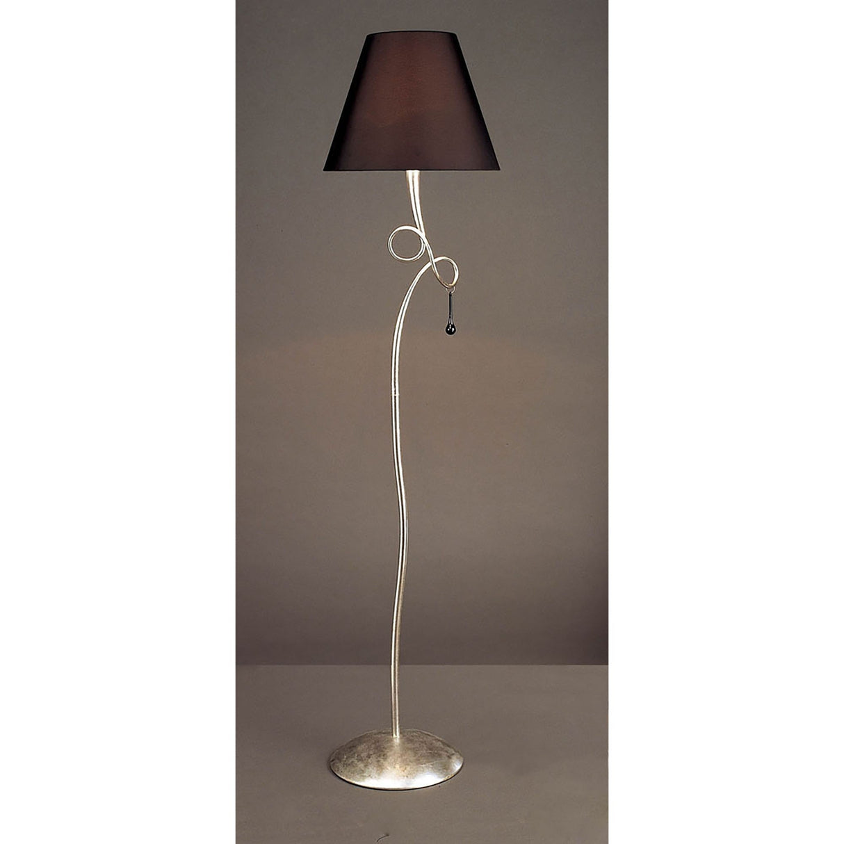 The Paola 1 Light Floor Lamp features a sleek silver curved stand, circular base, black shade, and decorative glass droplets near the top. The background is plain and neutral.