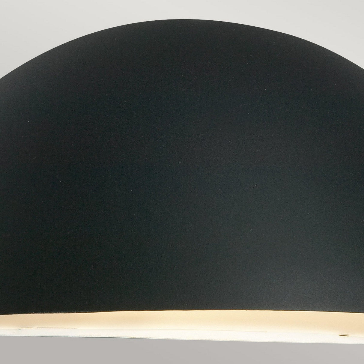 A close-up view of the Paris Outdoor Large 1 Light Wall Lantern in a modern black finish, featuring a smooth, dome-shaped design. The bottom emits a soft, glowing light against a neutral background.