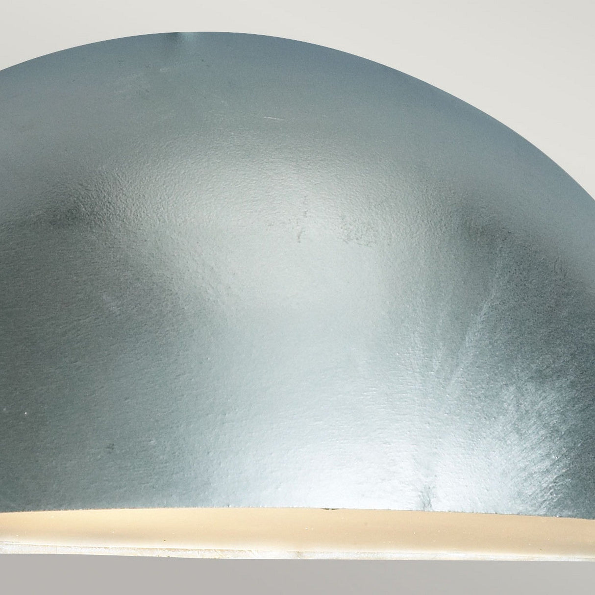 Close-up of the Paris Outdoor Small 1 Light Wall Lantern - Silver, showcasing its dome-shaped design crafted from galvanized steel. It features a smooth, silvery-grey texture with a lower edge highlighted in a brighter shade, reminiscent of outdoor lighting, all set against a neutral background.