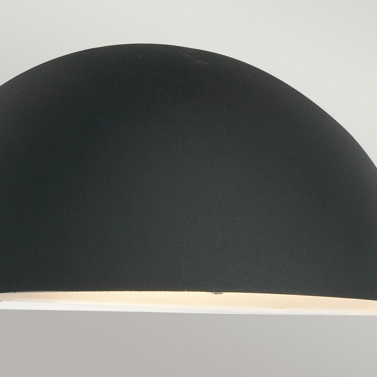 Close-up of the Paris Outdoor Small 1 Light Wall Lantern in black, showcasing its sleek dome shape and smooth finish, with a portion of the softly illuminated interior visible against a neutral background.