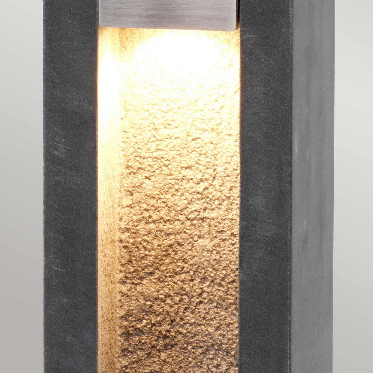 Introducing the Parkstone Large LED Bollard, featuring a modern, rectangular design. This wall-mounted fixture combines concrete with basalt stone elements and stainless steel for a textured surface. It emits a warm glow that beautifully highlights the intricate details of its inner section.