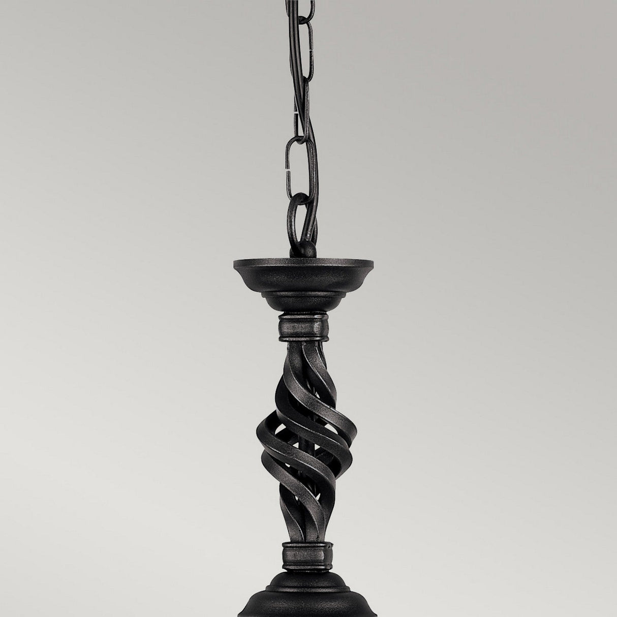 Close-up of the Pembroke 1 Light Pendant - Black, crafted from twisted hand-forged iron, hanging by a chain against a light gray backdrop. The elegant design highlights beautifully intertwined spiral elements.