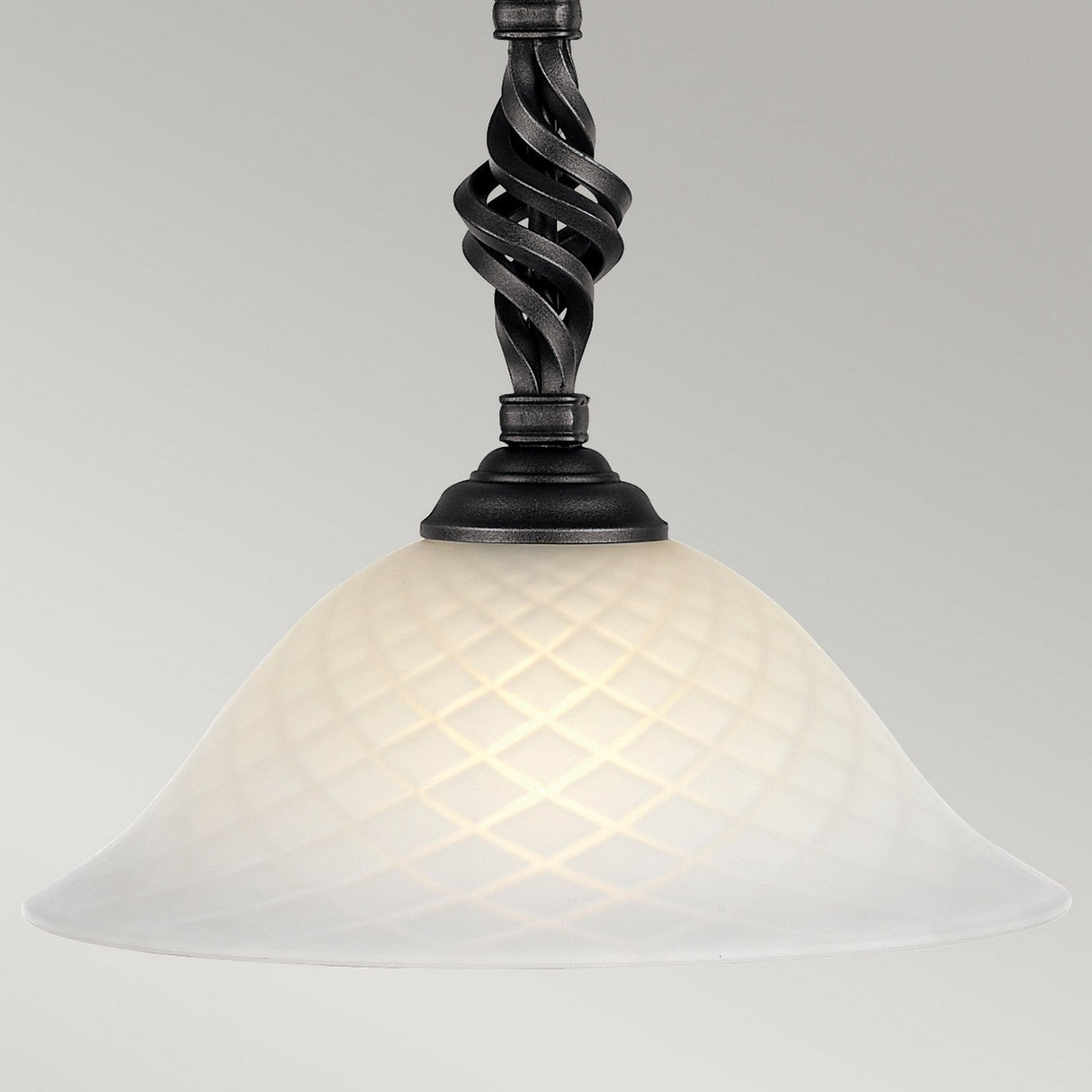 The Pembroke 1 Light Pendant - Black is a stunning hanging light, featuring a frosted glass shade adorned with a diamond pattern. Its hand-forged iron rod boasts an intricate twisted design in a smooth black finish, casting a gentle, warm glow.