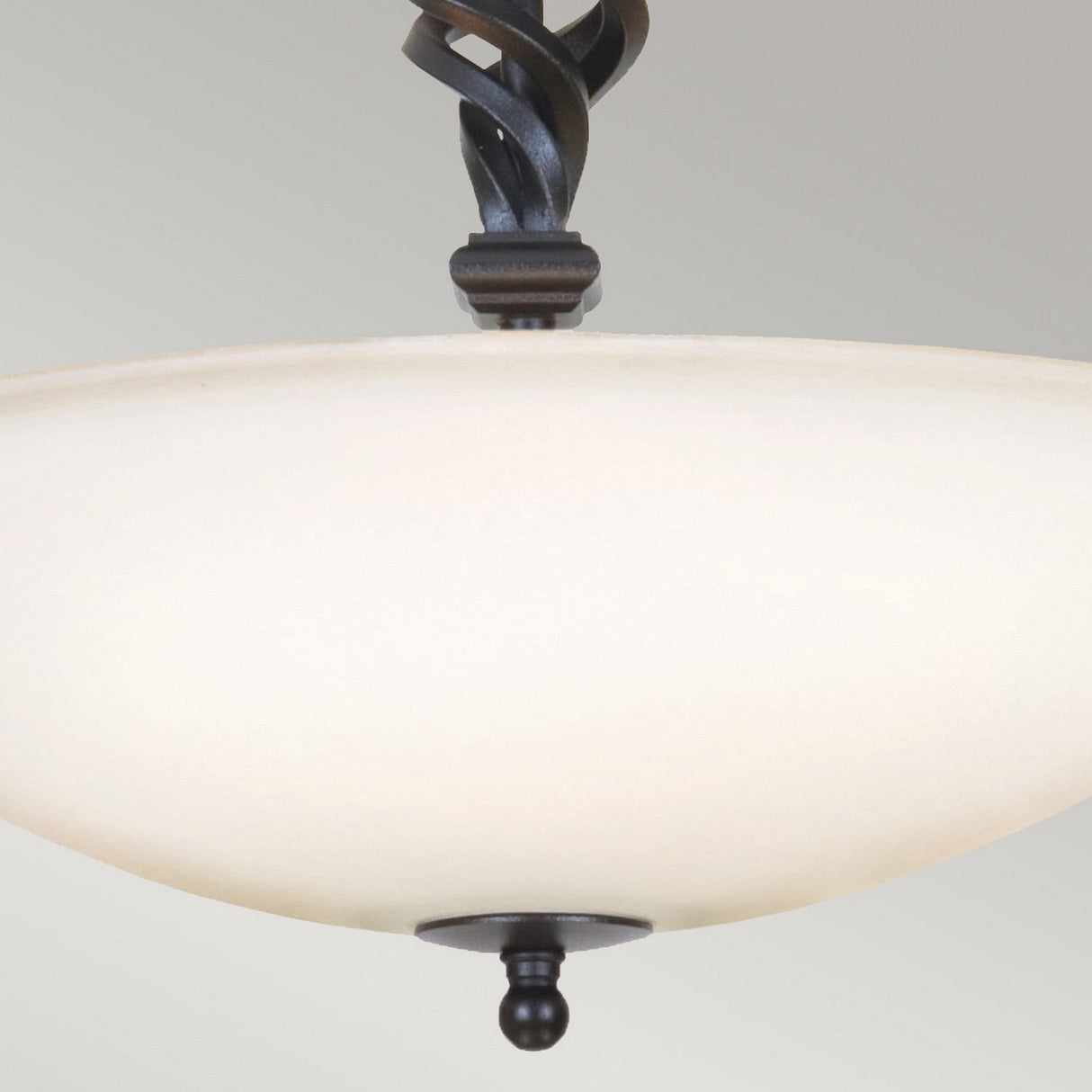 Close-up of the Pembroke 3 Light Semi Flush in black, showcasing its frosted glass bowl shape. It features traditional craftsmanship with a dark metal finial and a hand-forged iron twisted rod, all set against a light gray background.