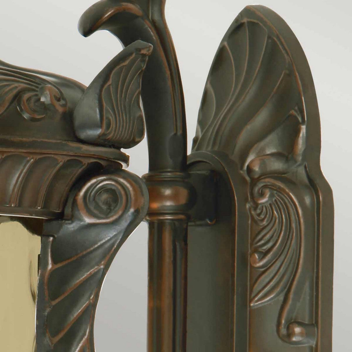 A detailed close-up of the ornate Philadelphia 3 Light Outdoor Large Wall Light in old bronze, showcasing its intricate swirling patterns and embossed leaf motifs. The IP44 rated design features curved lines and decorative accents, offering an elegant and vintage look perfect for an outdoor wall light.