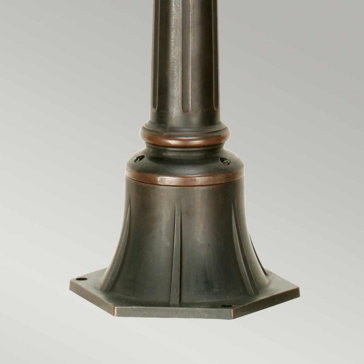 The Philadelphia 1 Light Medium Pillar in Old Bronze showcases a close-up view of an elegantly designed bronze outdoor lamp post base, featuring a tapered structure and a hexagonal mounting plate to enhance the sophistication of outdoor lighting.