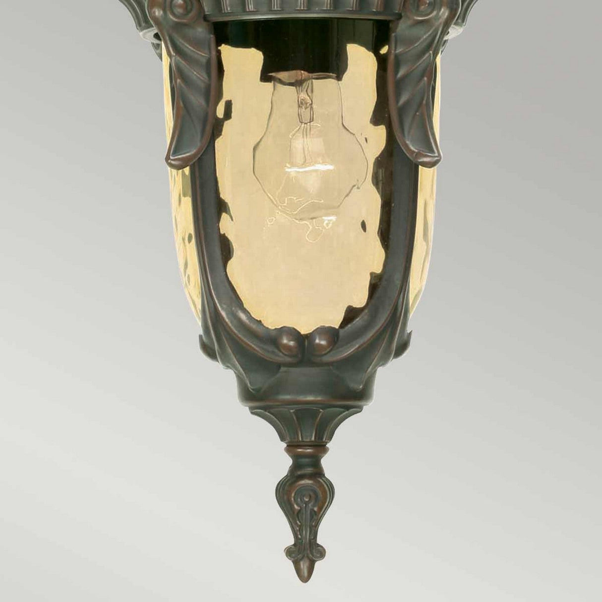 The Philadelphia 1 Light Outdoor Medium Chain Pendant showcases period-style elegance with its Old Bronze finish and clear glass shade, which reveals an exposed light bulb inside. The design is highlighted by decorative details and a pointed bottom finial, set against a neutral gradient background.