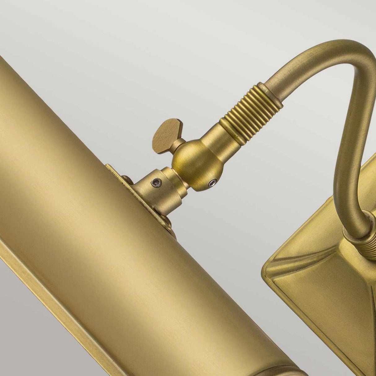 Close-up of the Picture Light 1 Light Small in Brushed Brass, a wall-mounted fixture featuring an adjustable arm and rectangular base. The design showcases a cylindrical light with a small adjustment knob and a vintage finish set against a neutral background.